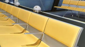 A bank of seats in a waiting area at Geneva airport. The seats are Yellow and have PLUTO built into them.