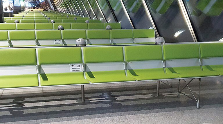 A bank of seats in Geneva Airport. The seats are green, and have TUF chargers built into them.